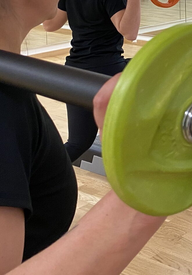 Ausschnitt von Teilnehmenden im Gruppenkurs Les Mills Bodypump mit Hantel auf der Schulter im Fitorama Gym in Basel