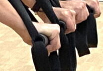 Hände halten die gelb-schwarzen TRX-Schlingen während eines Suspension Gruppenkurs Trainings im Fitorama Basel.